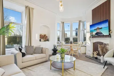 a living room with white furniture and a fireplace at Large Terraced Home with Parking in Glasgow