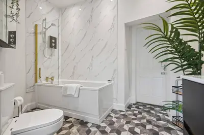a bathroom with a tub and a toilet and a sink at Large Terraced Home with Parking in Glasgow