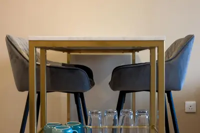 a table with two chairs and glasses under it at Netherbrae Apartment in Oban