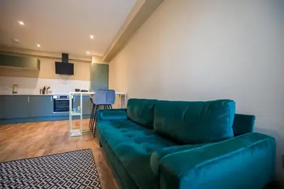 a living room with a green couch and a kitchen at Netherbrae Apartment in Oban