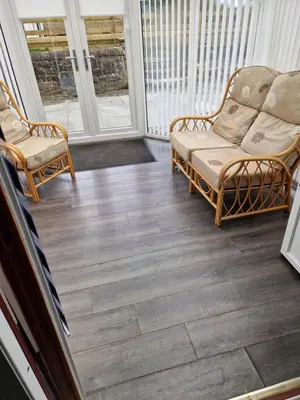a screened porch with two chairs and wood flooring at The Cottage in Kirk of Shotts