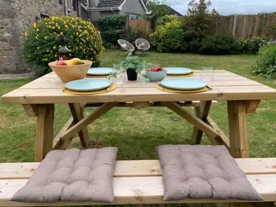 a wooden picnic table with plates and fruit on it at The Gower Cottages in Moffat