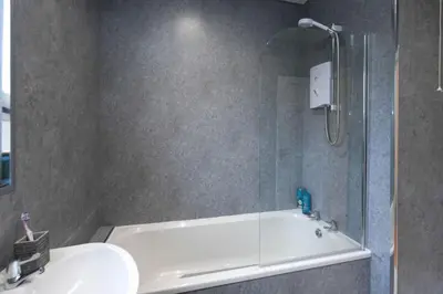 a bathroom with a shower and a tub and a sink at Barassie Villa located near Troon in Troon