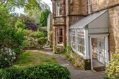 a brick house with a white door and a yard at Victorian Charm - Lush Garden, Shops and Parking in Edinburgh