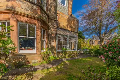 an old brick house with a garden in front of it at Victorian Charm - Lush Garden, Shops and Parking in Edinburgh