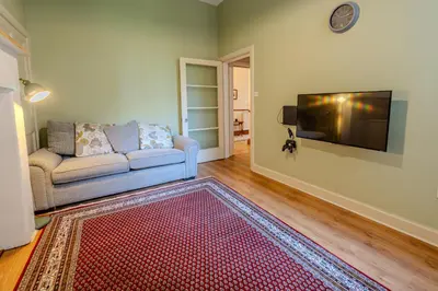 a living room with a couch and a flat screen tv at Victorian Charm - Lush Garden, Shops and Parking in Edinburgh