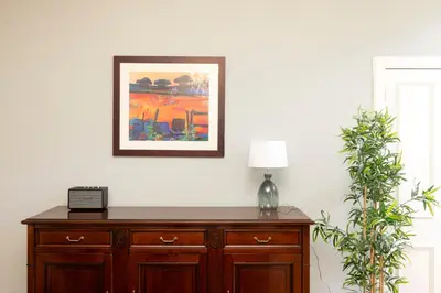 a wooden cabinet with a lamp and a picture on the wall at Stylish 1-Bedroom Edinburgh Apartment in Edinburgh