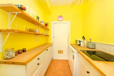 a kitchen with yellow walls and wooden counter tops at Stylish 1-Bedroom Edinburgh Apartment in Edinburgh