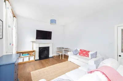a living room with a white couch and a fireplace at Charming Edinburgh Apartment with 2-Bathroom and Private Entrance in Edinburgh