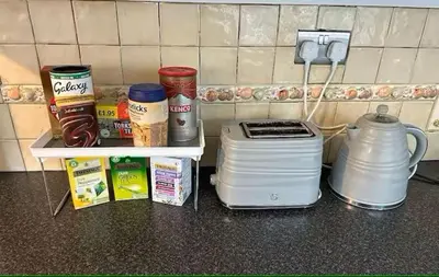 a kitchen counter with a shelf with food and a blender at 5BR House w Garden Near Stadium in Moffat