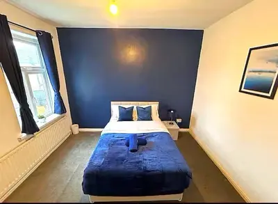 a bedroom with a bed in the corner of a room at 5BR House w Garden Near Stadium in Moffat