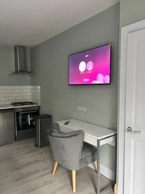 a kitchen with a table and a television on the wall at The Dixon - Commonwealth Games 2026 in Glasgow