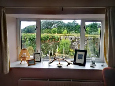 a window sill with a view of a garden at Cosy cottage near Thornhill in Closeburn