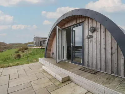 a circular house with a large window on a deck at Sula in Oban