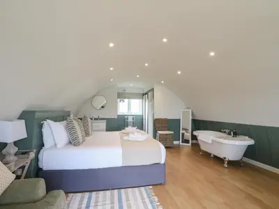 a bedroom with a bed and a tub and a sink at Sula in Oban