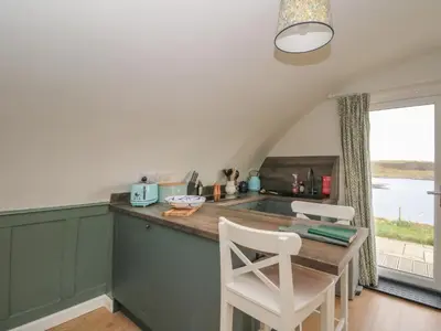 a kitchen with green cabinets and a table and chairs at Sula in Oban