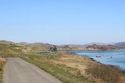 a road on a hill next to a body of water at Torsa in Oban