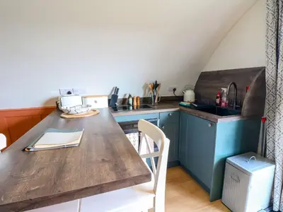 a kitchen with a wooden table and a counter top at Fladda in Oban