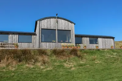 a wooden house with windows on top of a field at WildLuing in Oban