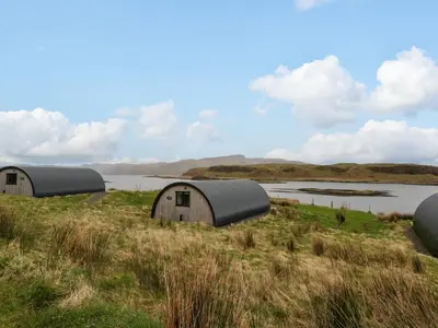 three domes in a field next to a body of water at Insh in Oban