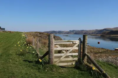 a wooden gate in the grass next to a river at Insh in Oban