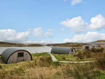 a group of domes in a field next to a body of water at Insh in Oban