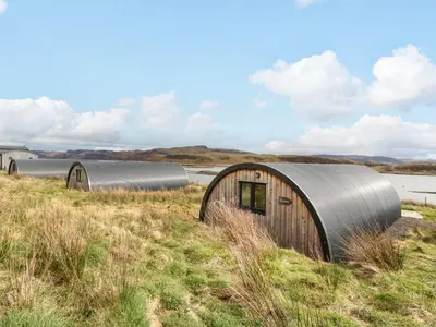 a group of circular buildings in a field with a body of water at Losal in Oban