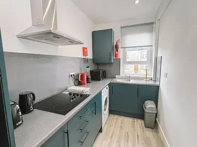 a small kitchen with blue cabinets and a sink at Itohan 3-bed Cottage Flat in Glasgow