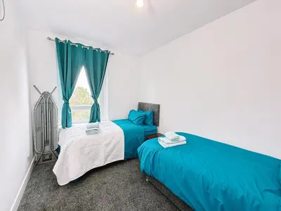 a bedroom with two beds and a window at Itohan 3-bed Cottage Flat in Glasgow