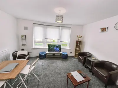 a living room with a table and chairs and a tv at Itohan 3-bed Cottage Flat in Glasgow