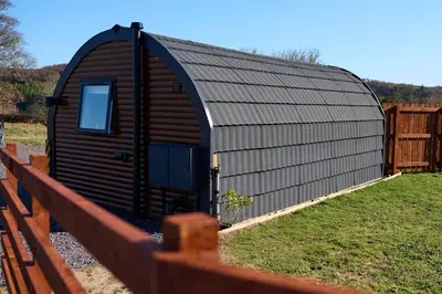a large wooden building with a gambrel roof on a fence at The Pods at 7 Black Crofts in Oban