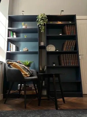 a black book shelf with a chair and a table at KKLM Holidays in Largs