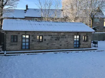 a small stone house with snow on the ground at The Owl Stony Snug in Carstairs Junction
