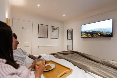 a woman sitting in a bed with a tray of food at Hamilton Residence - Private Main Door 1BR in Glasgow
