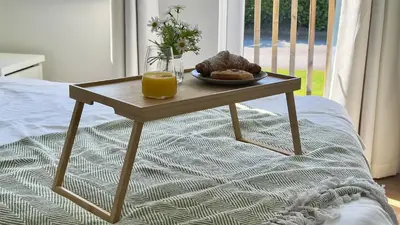 a table with a plate of food and orange juice on a bed at The Tummel Lodge with Hot Tub in Crieff in Crieff
