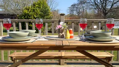 a wooden table with plates and glasses of red wine at The Tummel Lodge with Hot Tub in Crieff in Crieff