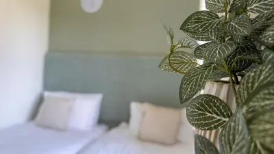 a green plant sitting next to a bed with pillows at The Tummel Lodge with Hot Tub in Crieff in Crieff