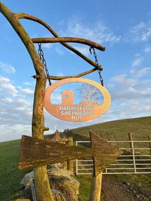 a sign hanging from a chain next to a tree at Barmoffity Shepherds Hut in Kirkpatrick Durham