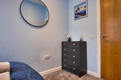 a bedroom with a mirror on the wall and a dresser at 2 bedroom, newly-renovated, comfortable town centre apartment! in Oban