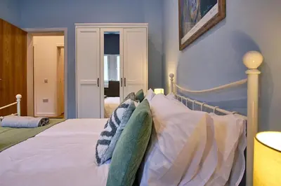 a bedroom with a bed with white sheets and pillows at 2 bedroom, newly-renovated, comfortable town centre apartment! in Oban