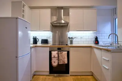 a kitchen with white cabinets and a stove top oven at 2 bedroom, newly-renovated, comfortable town centre apartment! in Oban
