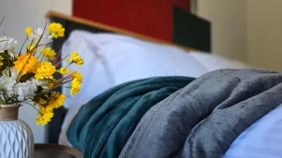 a bed with a vase of flowers and a blanket at The Ansi9 in Livingston