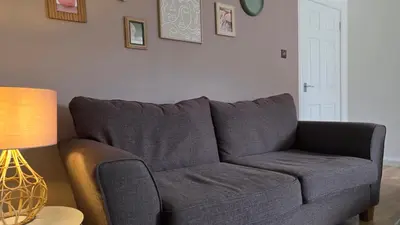 a gray couch in a living room with a lamp at The Ansi9 in Livingston