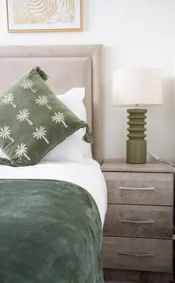 a bed with a green pillow and a lamp on a night stand at Bartonshill House in Glasgow