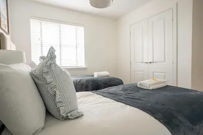 a white bedroom with two beds and a window at Bartonshill House in Glasgow