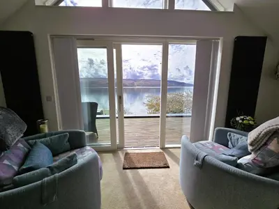 a living room with two couches and a large window at Fyne Edge - A Luxurious Lochside Haven in Minard