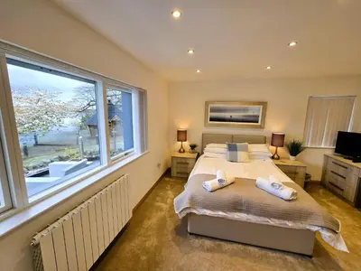 a bedroom with a bed and a large window at Fyne Edge - A Luxurious Lochside Haven in Minard
