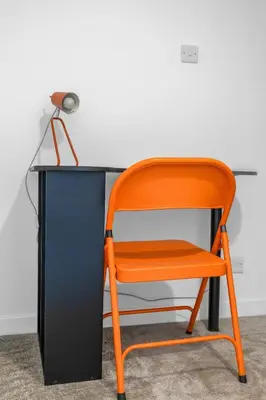 a orange chair sitting in front of a desk at Appin House -Cosy 2 bed house in Dunfermline in Dunfermline