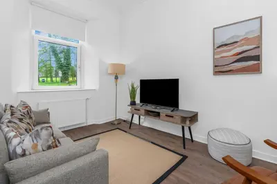 a living room with a couch and a tv at Appin House -Cosy 2 bed house in Dunfermline in Dunfermline