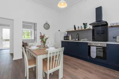 a kitchen with a wooden table and blue cabinets at Appin House -Cosy 2 bed house in Dunfermline in Dunfermline
